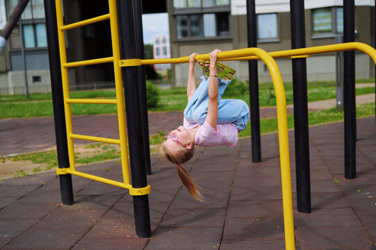 Happy child playing upside down on the monkey bars