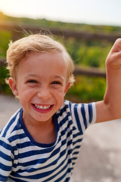 Young boy smiling outdoors during summer vacation, expressing happiness, joy, and positive childhood emotions