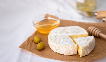 Camembert cheese with honey and olives served as an appetizer with white wine. Close-up. Copy space.