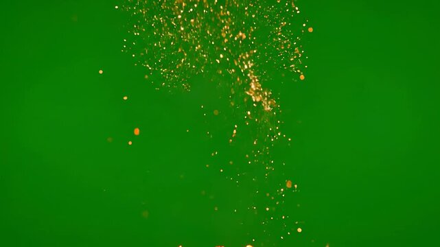 Golden sparks and floating embers rising on green background, abstract particle effect