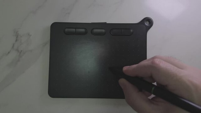 Artist hand uses a black digital stylus pen to sketching and a graphics tablet at a sleek marble workspace
