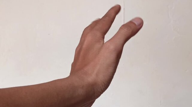 a human hand making different gestures against a plain white wall, demonstrating hand movements and nonverbal communication.