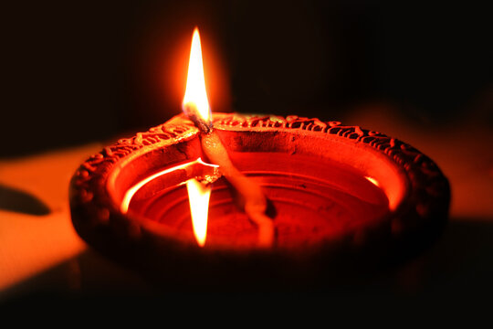 Traditional Clay Diya Burning with Flame on Diwali Festival, Beautiful Illuminating Terracotta Oil Lamp Against Dark Background for Deepavali Celebration High Resolution Stock Photo