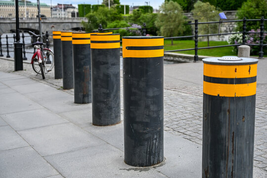 Retractable security bollards providing pedestrian protection and anti-terrorist defense on a city pavement. Automatic rising bollards installed on pavement. Pedestrian protection.