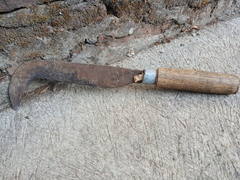 Traditional Rusty Sickle with Wooden Handle on Concrete Floor