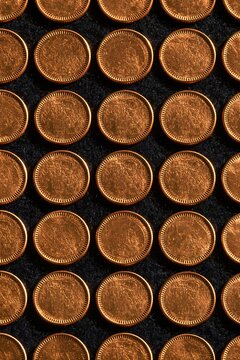 Rows of plain gold coins arranged on a dark felt surface, featuring a metallic glow and reeded edges for financial patterns and packaging design