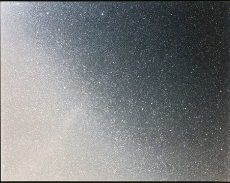 Microprismatic retroreflective material with a sparkling cube-corner structure, featuring a luminous silver glow on a grey field for industrial backgrounds