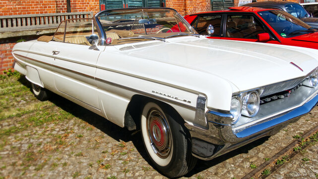 White 1961 oldsmobile dynamic 88 convertible standing at an outdoor vintage car show