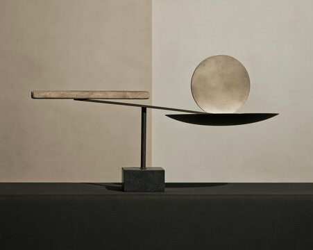 Beam balance scale with a metal disc and bar, featuring a matte finish and hard directional lighting for comparison and asset allocation, with copy space