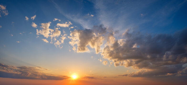 A stunning sunset paints the sky with vibrant colors as clouds drift peacefully, creating a dramatic atmosphere at dusk.