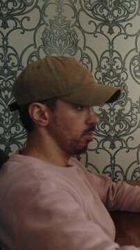 A man sits comfortably at home working on a computer and editing video footage. The scene shows a modern creative workflow with video editing software, timeline adjustments