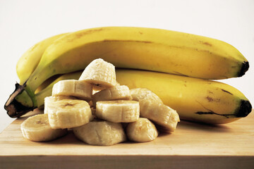 Banana slice on wooden cutting board on white background © Yudy Pirmansah
