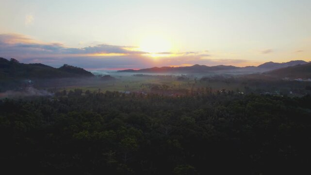 East Java, Indonesia - 01 September 2026: Aerial view of Red Island Beach at sunrise with mist over the lush forest and distant hills.
