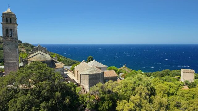 Aerial drone two shot edit of Pino authentic mountain village in Cap Corse Corsica France. Bell tower convent and scenic green nature landscape 4K stock video