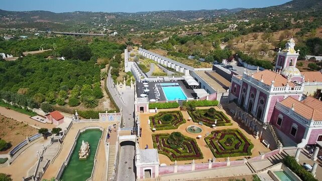 Majestic aerial view of estoi palace in the algarve, portugal, highlighting rococo architecture, formal french gardens, fountains and pools at this historic luxury pousada and landmark