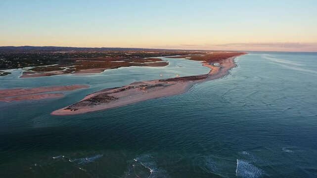 Stunning aerial perspective flying over the serene waters and sandbanks of ria formosa natural park in algarve, portugal, capturing the tranquil beauty of the coastline during a colorful sunset