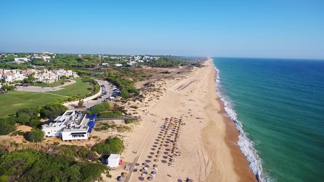 Beautiful aerial footage showing the stunning coastline of praia de garrao in vale do lobo, algarve, portugal, with its golden sands, calm ocean waves, and luxury beachside resort