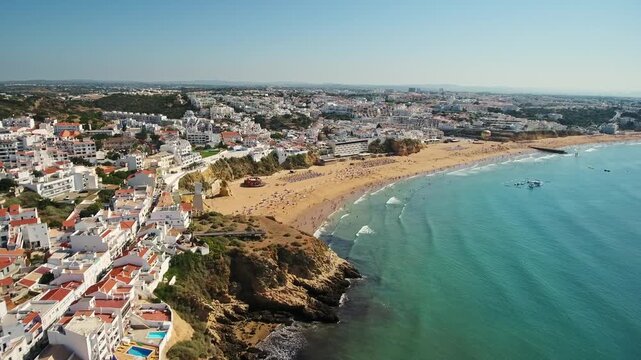 Beautiful aerial footage flying over the historic old town and sunny fisherman's beach in albufeira, a popular tourist destination and resort city in the algarve region of southern portugal