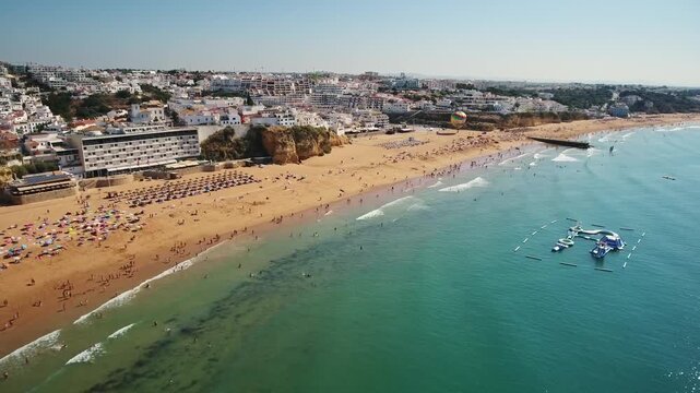Beautiful aerial view showing the sandy praia dos pescadores, or fishermen's beach, with tourists swimming and relaxing under the sun in the coastal city of albufeira, portugal