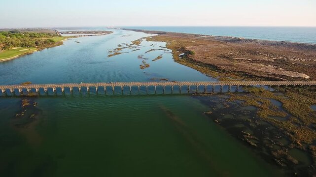 Beautiful aerial view of the iconic wooden footbridge at quinta do lago, crossing the scenic ria formosa estuary and connecting to the beach, a famous tourist landmark in algarve, portugal