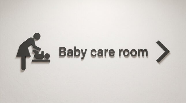 Black baby care room sign with a baby changing icon and a directional arrow on white wall with wall mounted