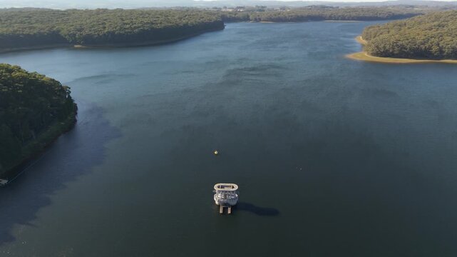 Silvan, Victoria, Australia - 01 September 2026: Aerial view of the Silvan Reservoir Park with its central water intake tower surrounded by calm dark water and dense forest landscape.