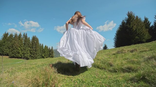 Bride runs uphill across a sunny meadow in a billowing white wedding gown, Dynamic outdoor movement conveys freedom romance and destination celebration