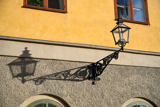 Street light. Classic ornate black metal outdoor wall lantern with a triangular scroll bracket. Traditional cast-iron wall lamp featuring decorative scrollwork and glass panes. 