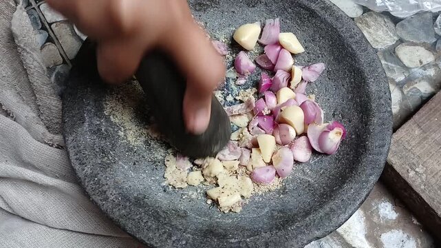Grinding Shallots Garlic and Spices with Traditional Stone Mortar and Pestle for Cooking