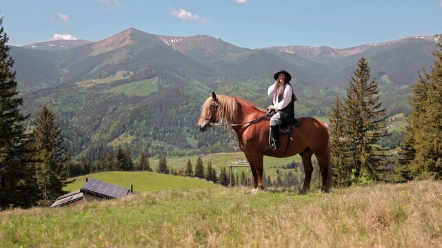 Female rider pauses on horseback above a panoramic green mountain valley, Scenic riding experience promotes outdoor leisure nature and rural exploration
