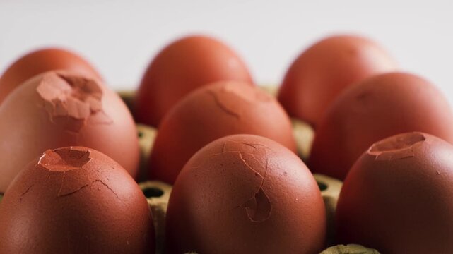 Close-up of brown eggs with cracked shells arranged in a carton. High quality 4k footage