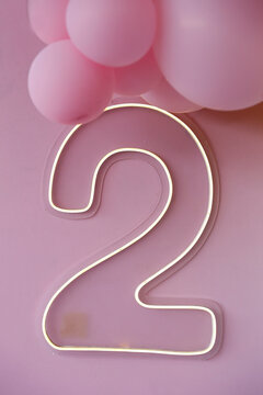 LED neon luminous sign in the shape of number two with colorful balloons