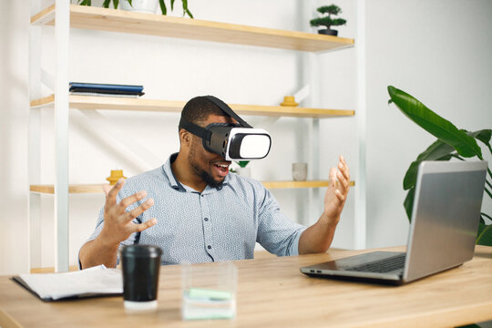 Black male entrepreneur sitting in office and using virtual reality glasses
