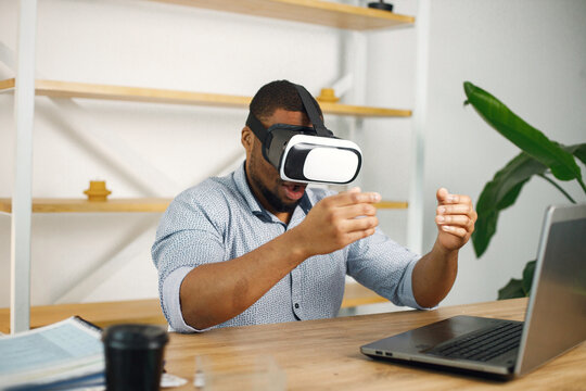 Black male entrepreneur sitting in office and using virtual reality glasses