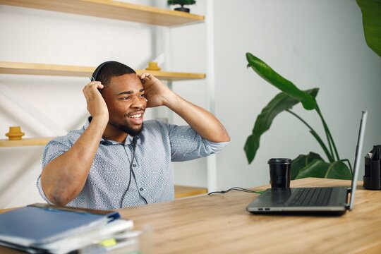 Black man sitting in office, wearing a earphones and make a video call
