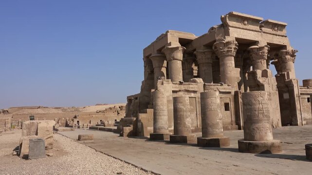 View of the ancient Temple of Kom Ombo with its massive stone columns and intricate hieroglyphic carvings under a clear blue sky in Kom Ombo, Aswan Governorate, Egypt.