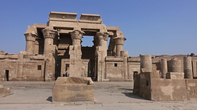 View of the ancient Temple of Kom Ombo with weathered stone columns and historic sandstone walls under a clear blue sky in Aswan, Aswan Governorate, Egypt.