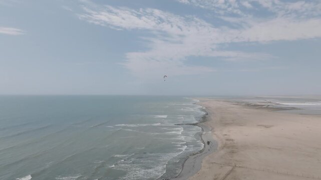 Aerial Drone Tracking Shot of Paraglider Flying Over Atlantic Ocean and Beach in Namibia