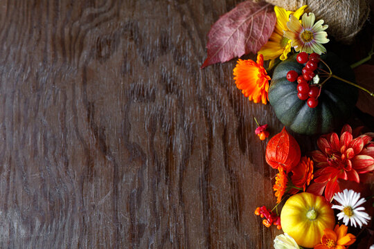 Autumn flat lay. Colorful pumpkins, autumn leaves, flowers border on rustic wooden table. Happy Thanksgiving. Fall season greeting card, space for text