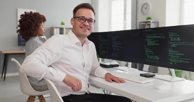 Programmer developer man coding software engineer in office. He codes on dual widescreen displays, collaborating in a bright workspace and writing clean code. Modern software work concept image.