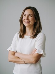 Obraz premium Confident businesswoman smiling with arms crossed in white shirt during studio portrait
