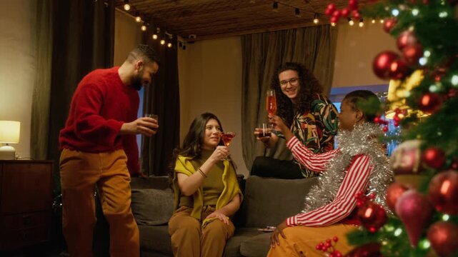 Diverse young friends toasting with cocktails near decorated Christmas tree during holiday celebration. Ideal for festive beverage advertising and seasonal party promotional videos