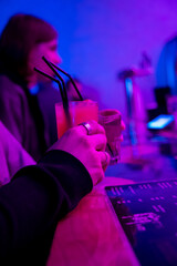 People enjoying drinks at a bar with colorful lights in the background during the evening © Chris