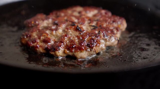 Homemade Burger Patty Sizzling in a Cast Iron Skillet