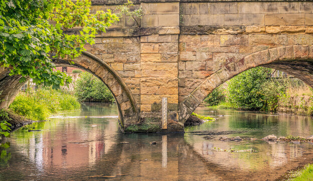 Ancient stone with a depth gauge reflected in the water below.