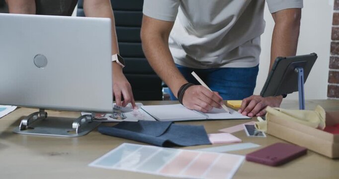 Colleagues are starting review, sketching and choosing swatches on laptop to refine layout at desk