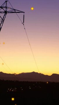 Animation of lens flares over transmission tower against silhouette of mountains