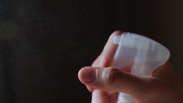 Hand spraying fine mist from a trigger spray bottle