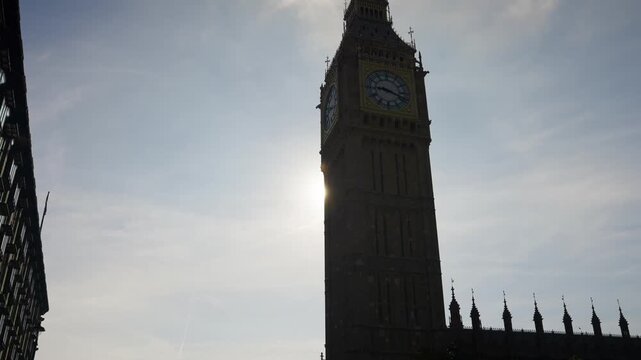 Clock tower silhouette with sun flare in urban city scene