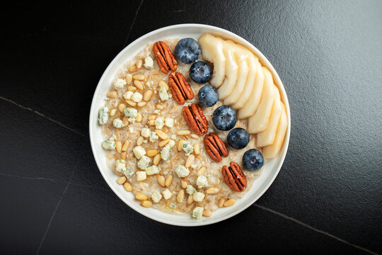 Oatmeal. Bowl of oatmeal porridge with blackberry, bananas and chia seeds on gray concrete old table background. Top view in flat lay style. Natural ingredients. Hot healthy breakfast and diet food
